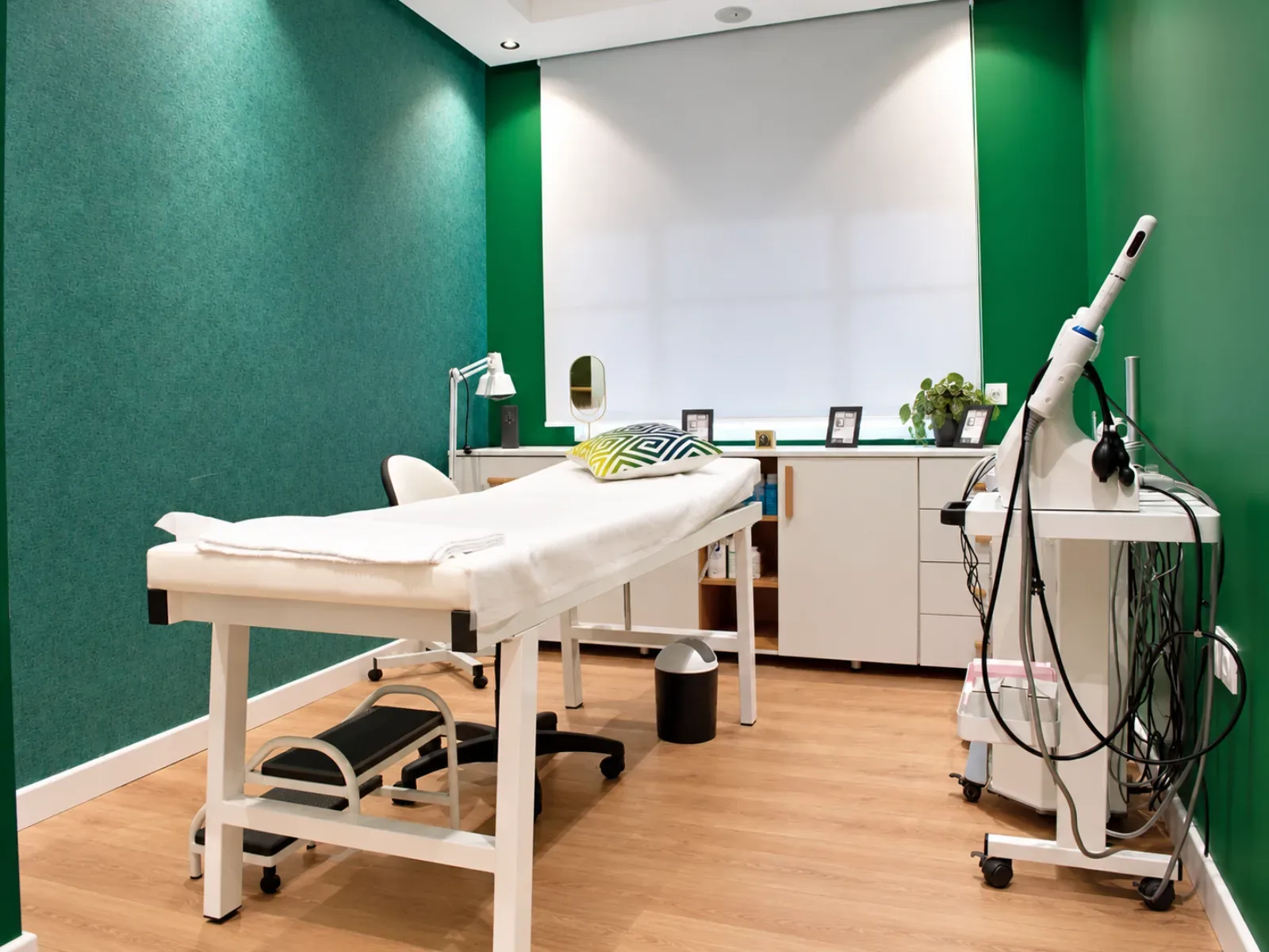 Salle de soins d’El Amrani Physio Clinica aux murs verts, avec table de traitement et appareil sur chariot